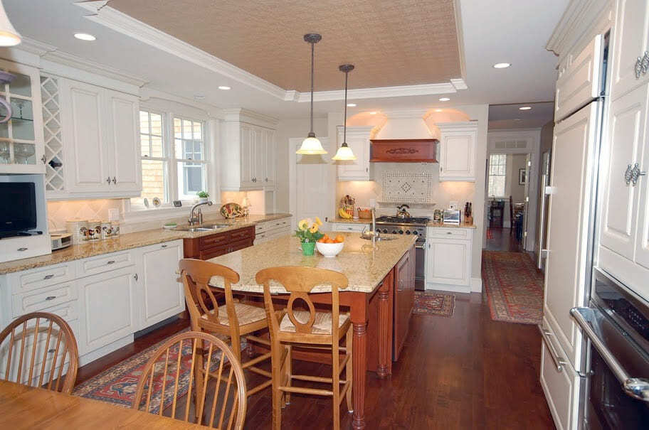 Bright kitchen with white cabinets, large island, granite counters, and hardwood floors in a New Hampshire home