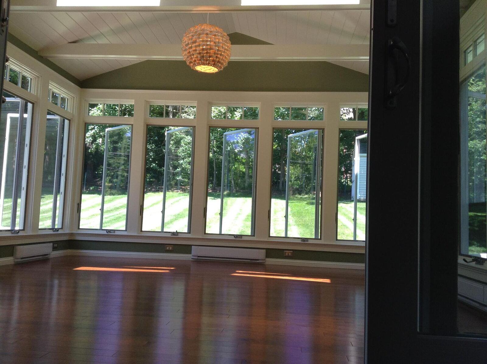Sunroom addition with large windows showcasing a bright backyard, completed by Oxland Builders in New Hampshire