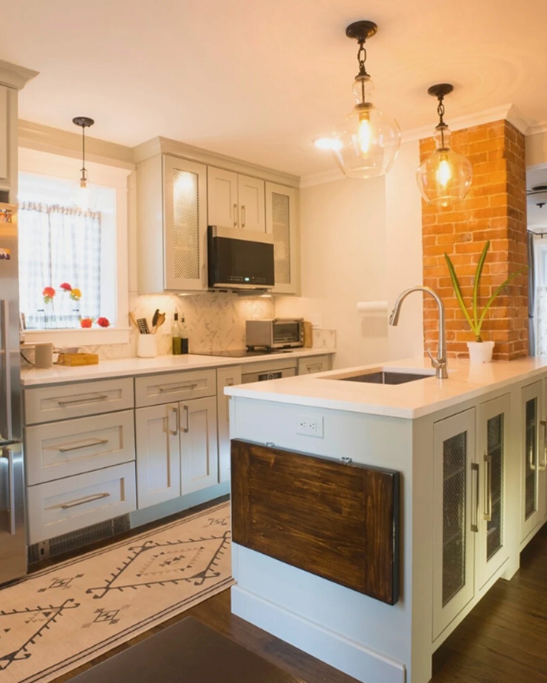 Modern New Hampshire kitchen with white cabinets, brick accents, and pendant lights over island