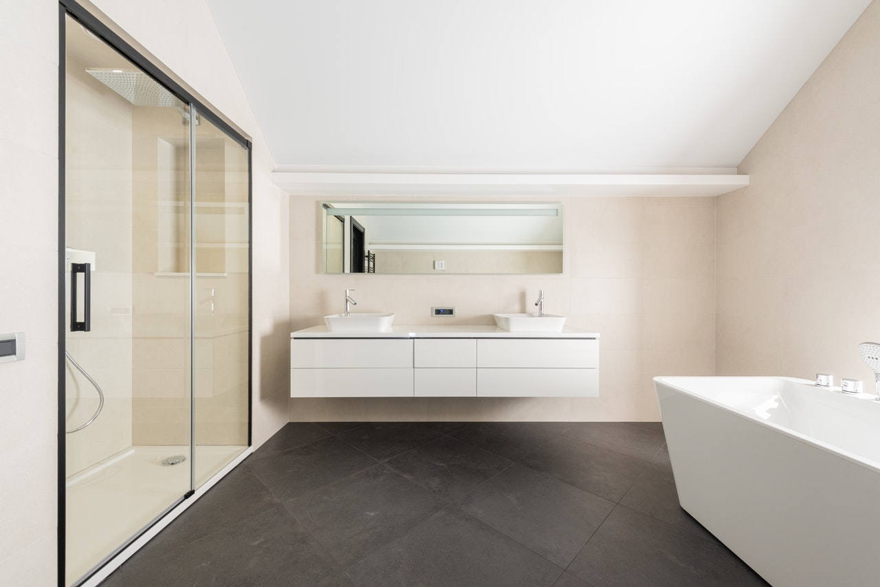 Modern bathroom in Coastal NH with glass walk-in shower, freestanding tub, double vanity, and sleek minimalist design