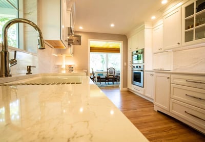 Bright kitchen with marble counters and modern fixtures by Oxland Builders in New Hampshire