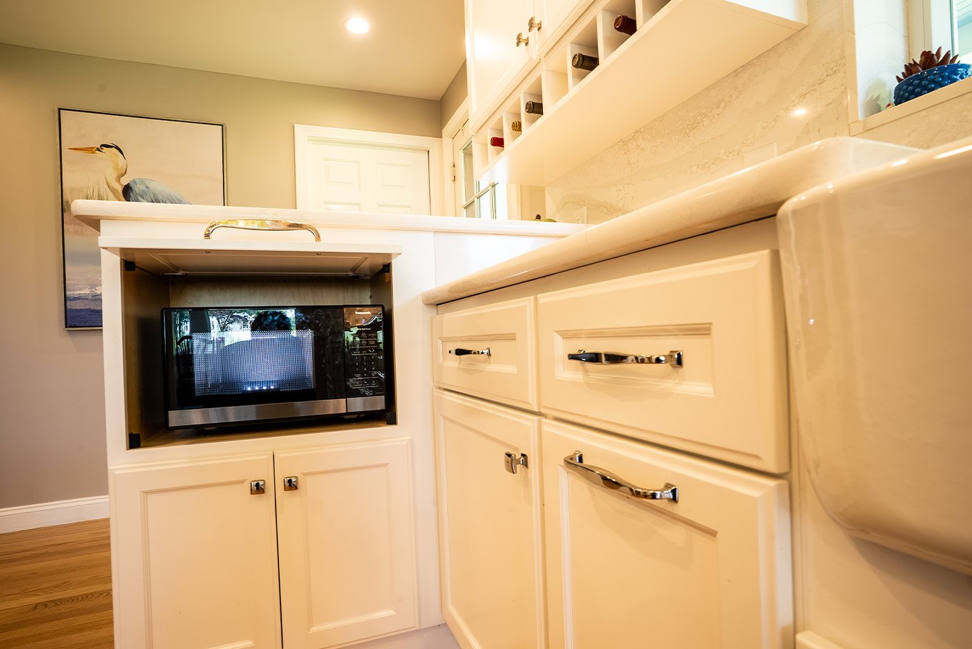 Hidden microwave drawer opened beneath sleek counters and built-ins in a coastal New Hampshire kitchen
