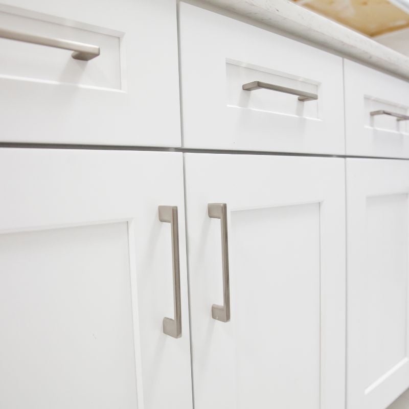 White shaker cabinets with brushed nickel pulls and quartz countertop detail by Oxland Builders