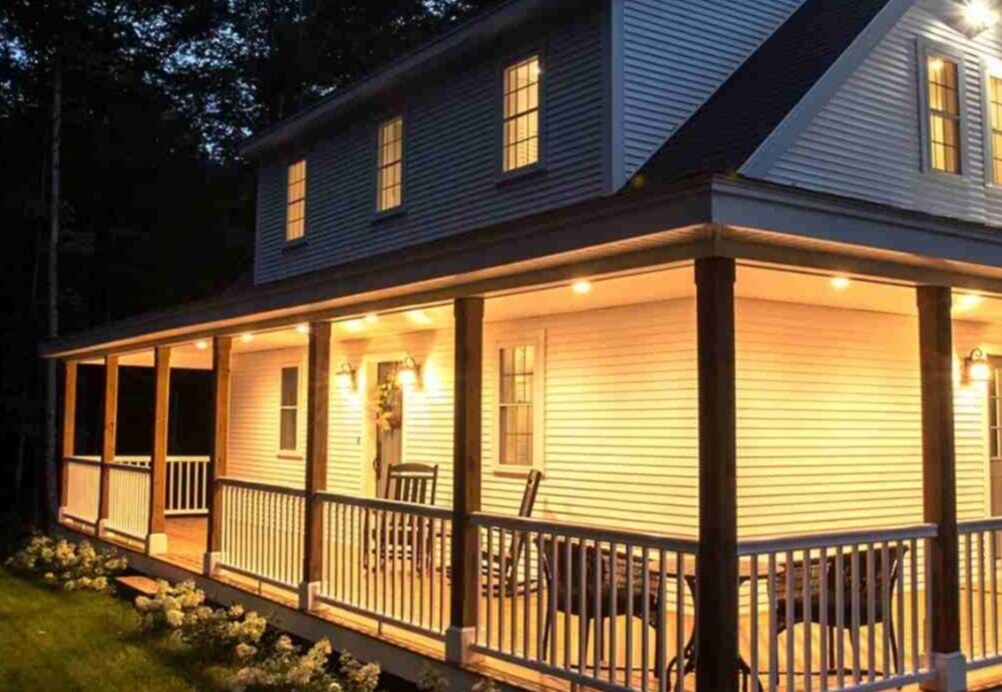 Wrap around porch with lighting on home exterior by Oxland Builders in New Hampshire