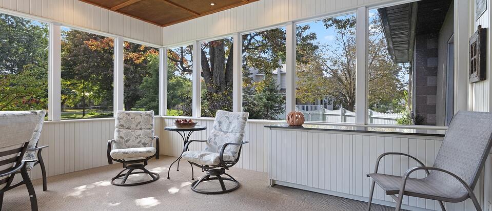 three season room with windows and comfy chairs