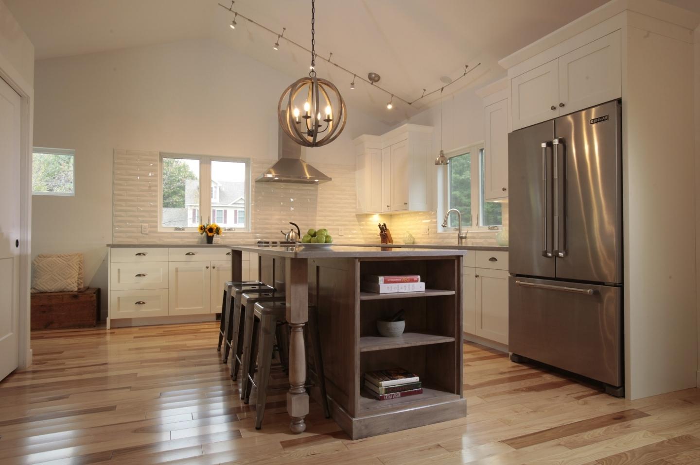 Circular pendant lighting above kitchen island with built ins by Oxland Builders in New Hampshire