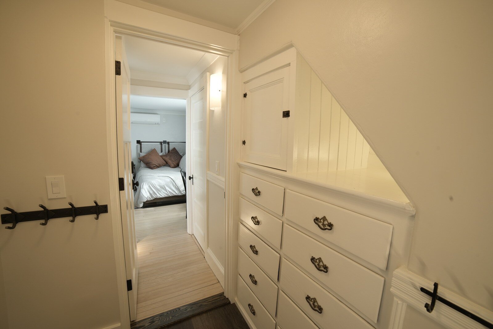 Hallway with built-in cabinetry leading to a cozy bedroom, a design by Oxland Builders in New Hampshire