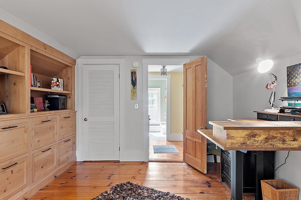 Home office with built-in wood cabinetry, desk, and hardwood floors in the Coastal New Hampshire area