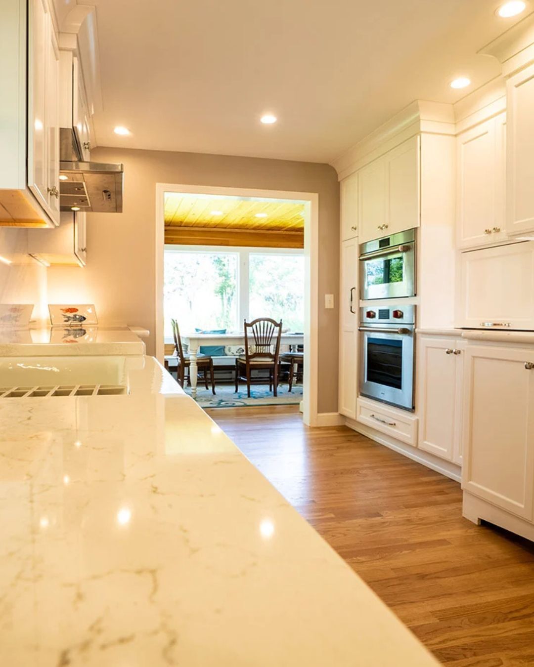 Bright kitchen with marble counters and modern fixtures by Oxland Builders in New Hampshire