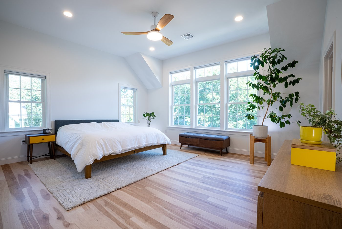 Spacious bedroom in coastal New Hampshire with white walls, light wood floors, and large windows filling the space with natural light